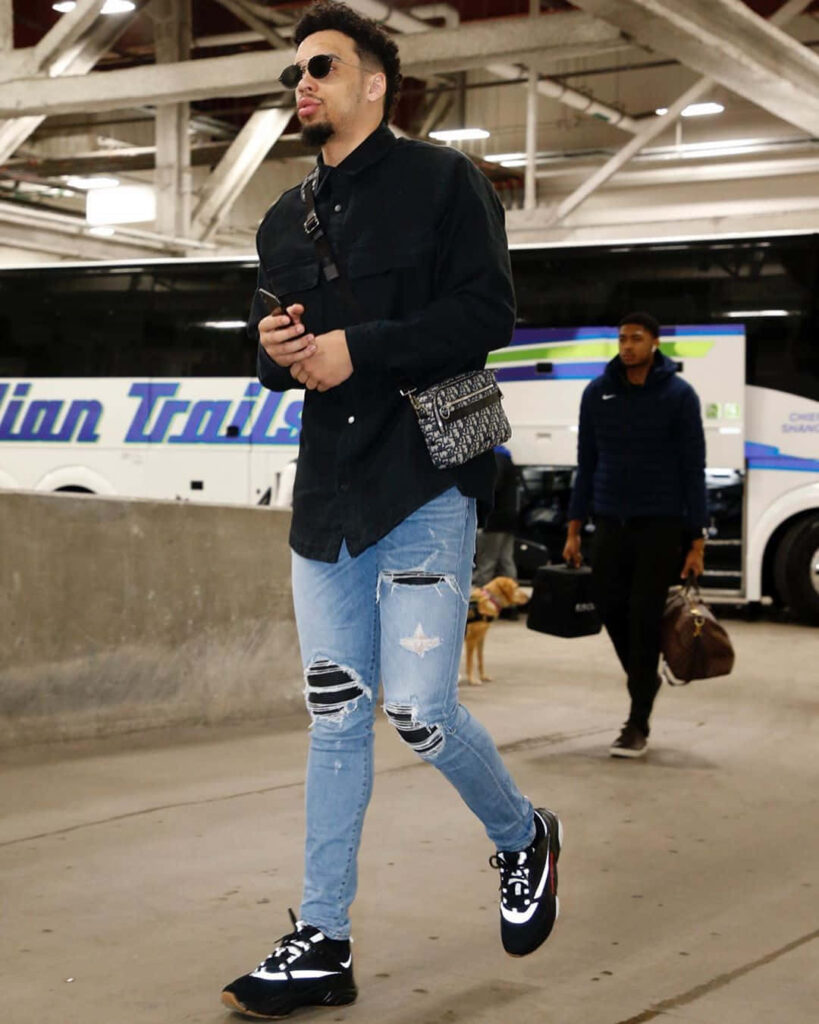 Dillon Brooks stylishly arriving in black shirt ripped jeans bold sneakers urban team bus background Wallpaper