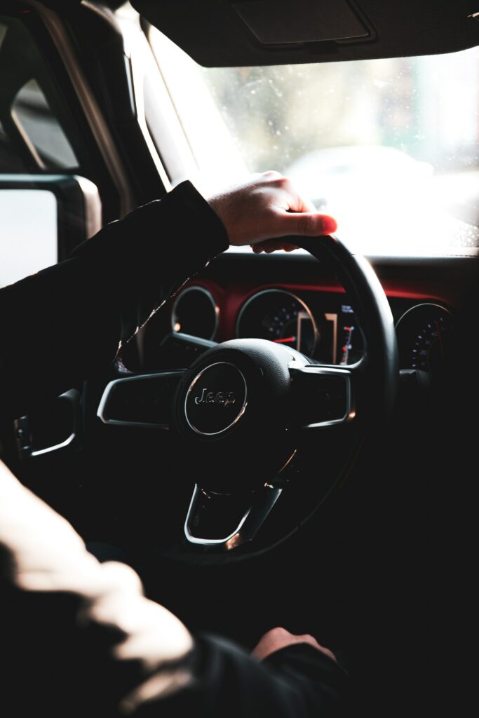 Close-Up Car Interior: Hand on Steering Wheel in Dim Lighting Wallpaper