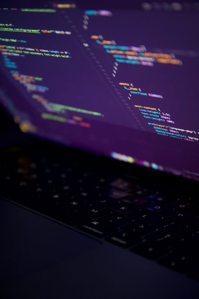 Dimly Lit Laptop Wallpaper: Vibrant Code in a Mysterious Setting
