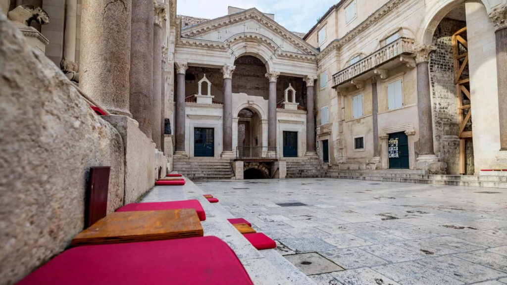Daytime view of Diocletian's Palace Croatia ancient architecture bright stone courtyard red seats Wallpaper