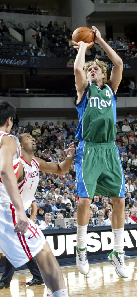Dirk Nowitzki midair jump shot in Dallas Mavericks uniform during intense NBA game action Wallpaper