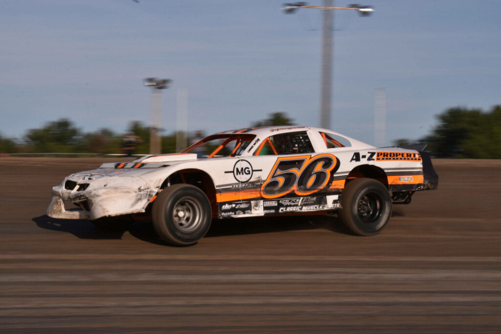Dirt racing car 56 drifting fast on dusty track with blurred trees and intense action wallpaper