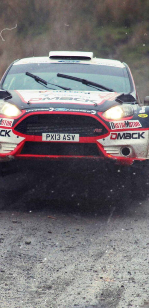 Determined rally car navigating muddy course in action-packed dirt rally race Wallpaper