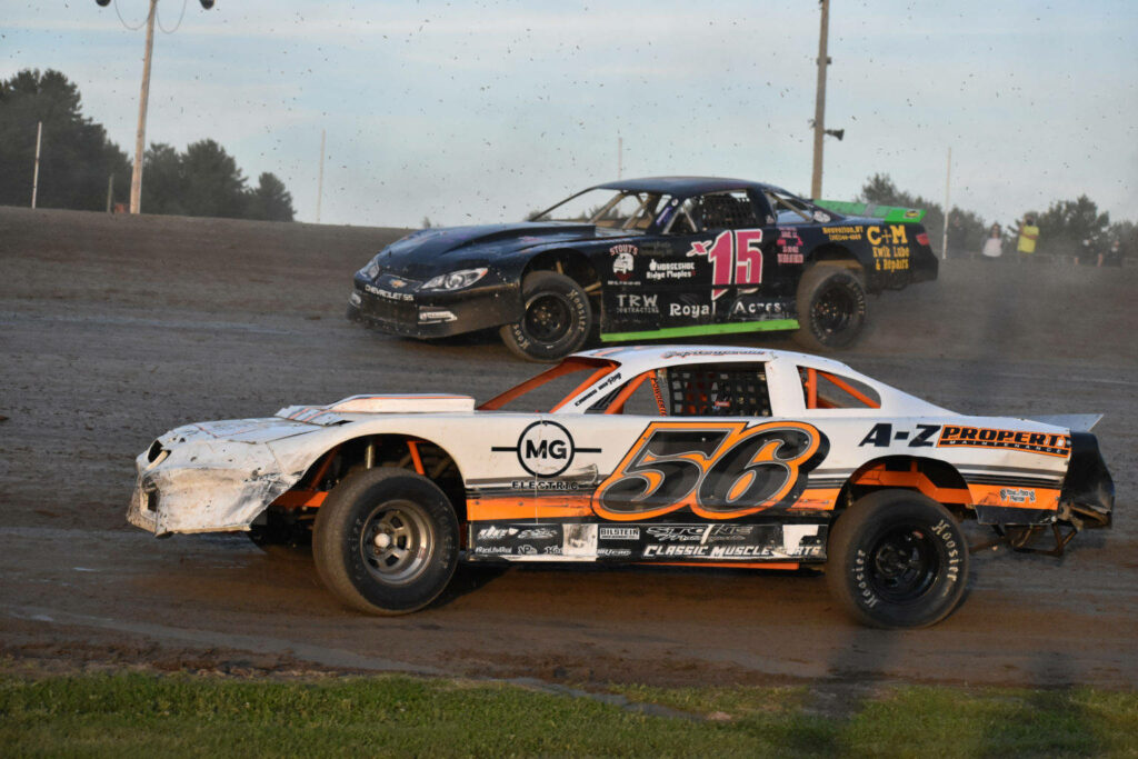 Two modified dirt race cars speeding on dusty track with white and orange number 56 in front Wallpaper