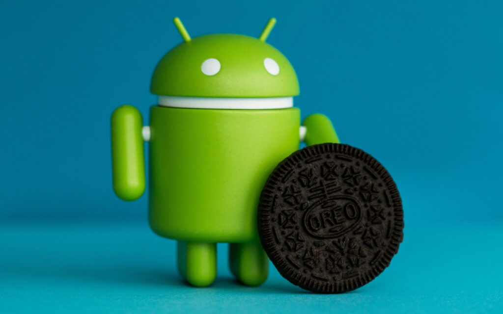 Android mascot standing next to Oreo cookie on blue background Android 8 wallpaper digital art