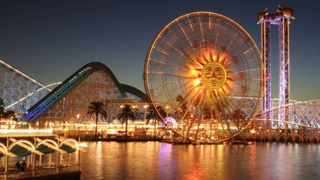 Sun Wheel glowing at night over water with roller coaster silhouette Disney California Adventure Wallpaper