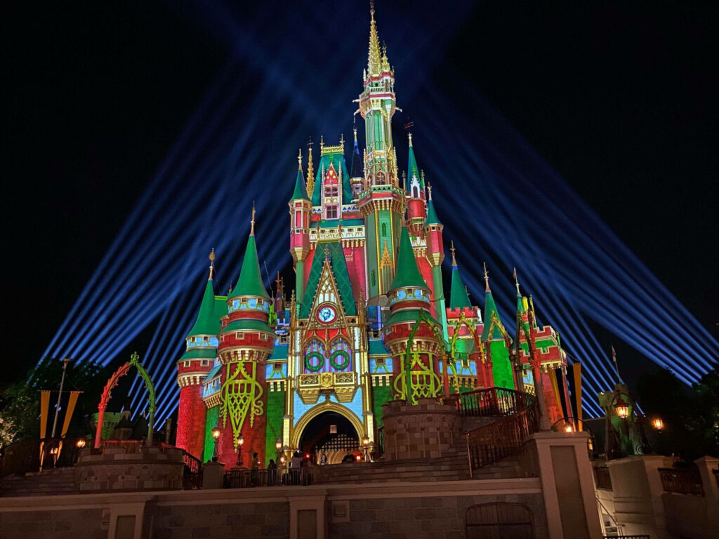 Disney Castle wallpaper lit in festive red green gold lights with magical Christmas night scene
