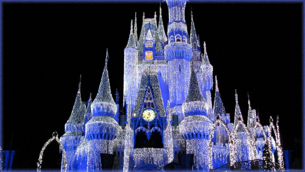 Disney Castle illuminated with white and blue lights at night magical fairy tale wallpaper background