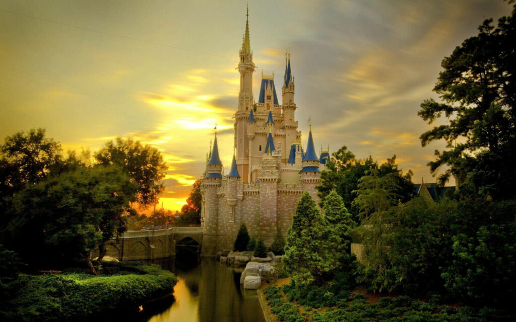 Disney Castle at sunset with golden light lush greenery and reflection in tranquil moat wallpaper