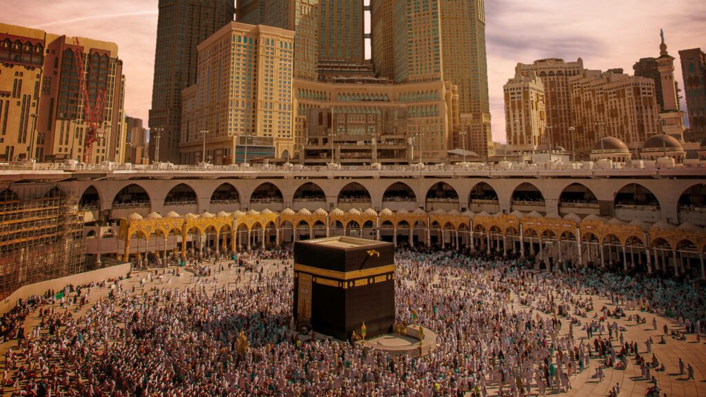 Rose-tinted photo of Kaaba and crowded Grand Mosque with Abraj Al-Bait towers in Mecca pilgrimage Wallpaper