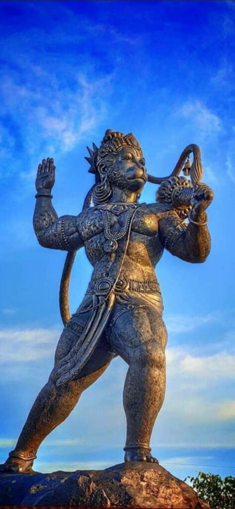 Majestic Hanuman: A Metallic God Stands Firm Against a Blue Sky Wallpaper