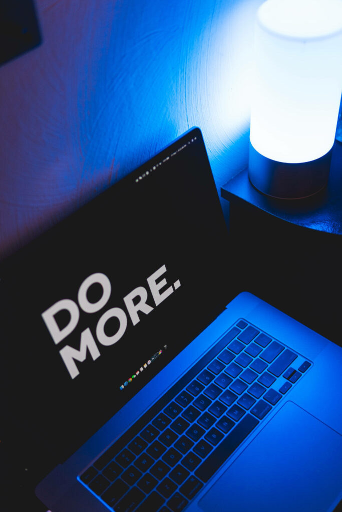 Motivational 'Do More' on MacBook Screen with Calm Blue Lighting Wallpaper