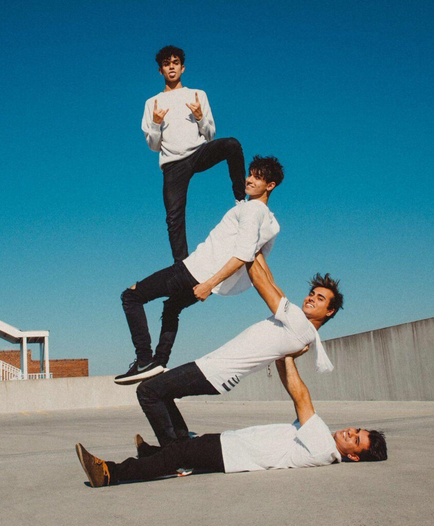 Dobre Brothers rooftop human pyramid in white outfits vibrant teamwork clear blue sky background Wallpaper