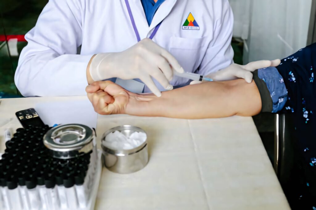 Doctor in white coat drawing blood from patient arm with syringe in clinical setting Wallpaper