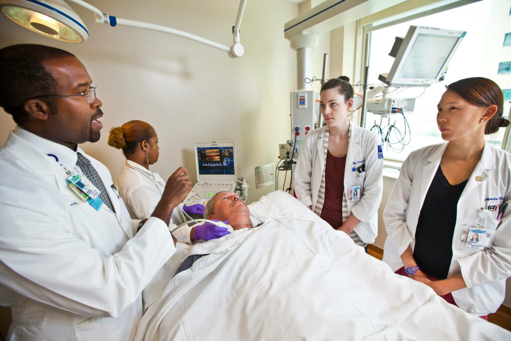Doctors in white coats consulting at hospital bedside showing teamwork and professional care Wallpaper