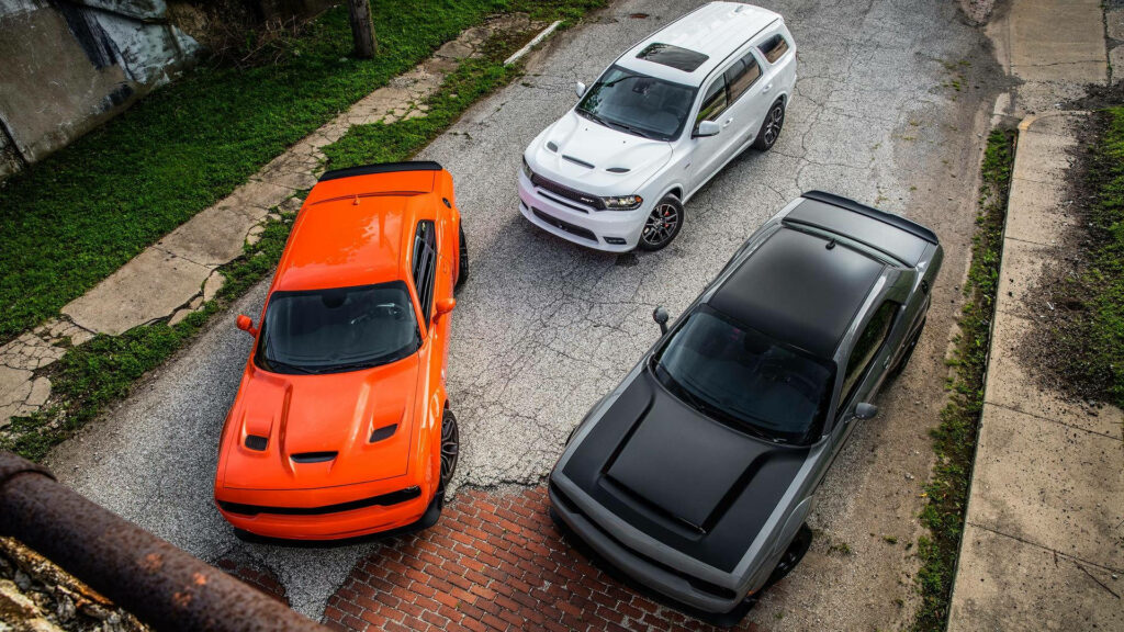 Trio of Dodge vehicles white Durango orange and dark grey muscle cars on urban textured road wallpaper