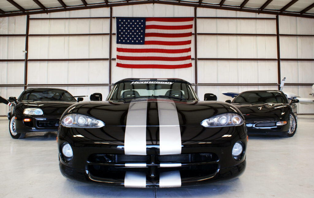 Dodge Viper sports car with white racing stripes in modern garage with American flag background Wallpaper
