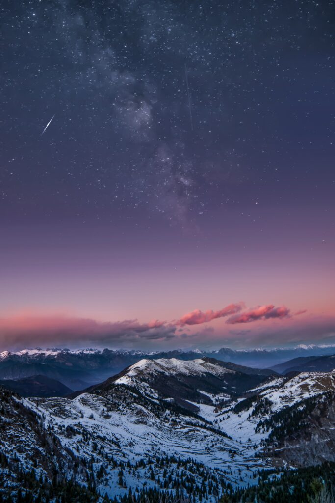 Snow-covered Dolomites at night under vibrant starry sky with pink clouds serene winter scene Wallpaper