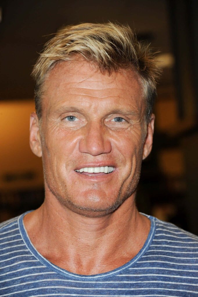 Close-up portrait of Dolph Lundgren with rugged features and striped shirt on blurred background Wallpaper