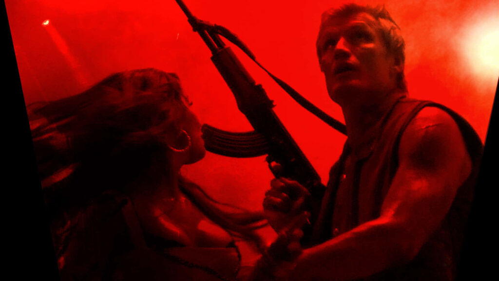 Dolph Lundgren in intense red-lit action scene holding rifle with determined rugged expression wallpaper