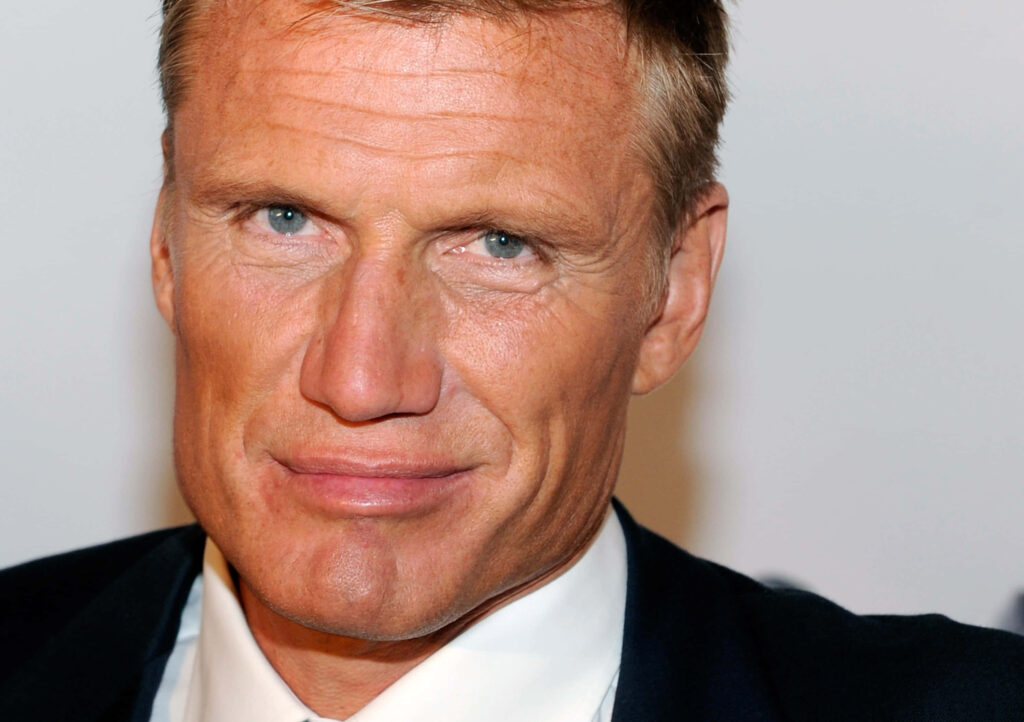 Dolph Lundgren close-up in sharp suit against white background confident expression wallpaper