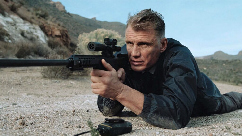 Dolph Lundgren in tactical gear aiming rifle prone on rocky terrain intense action scene wallpaper