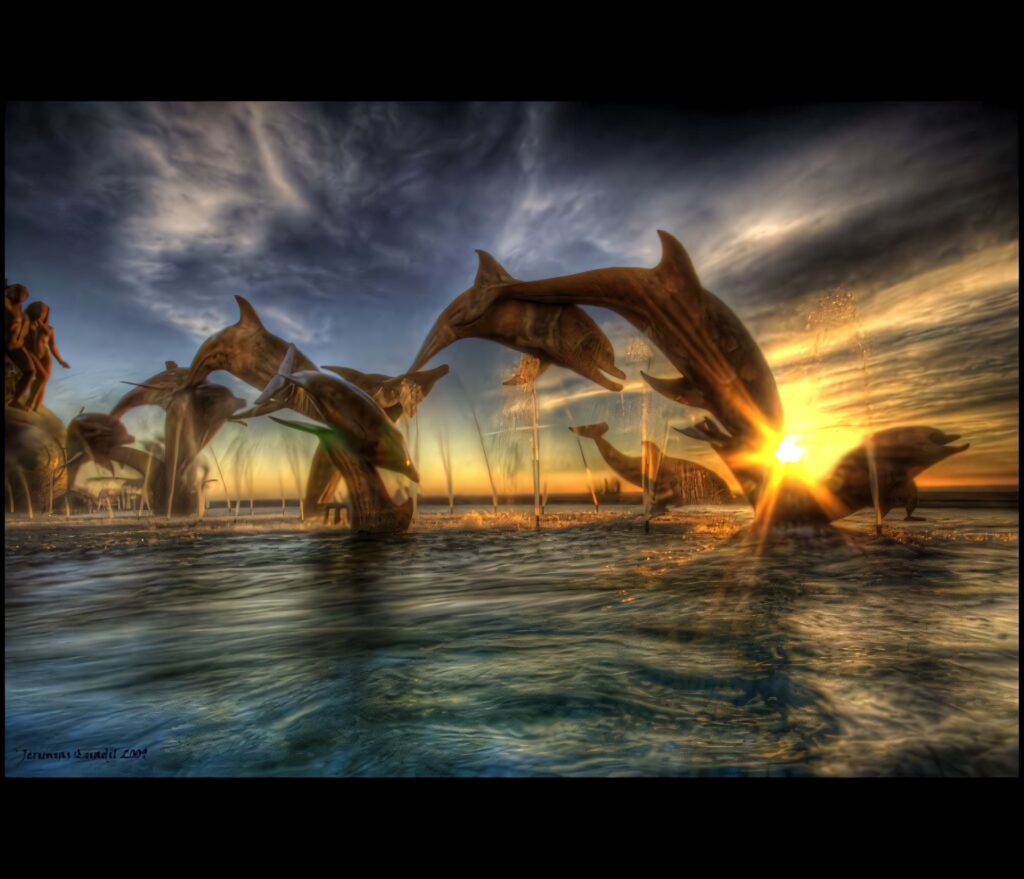 Dolphins leaping over sparkling water at vibrant sunset with golden hues and dramatic clouds Wallpaper