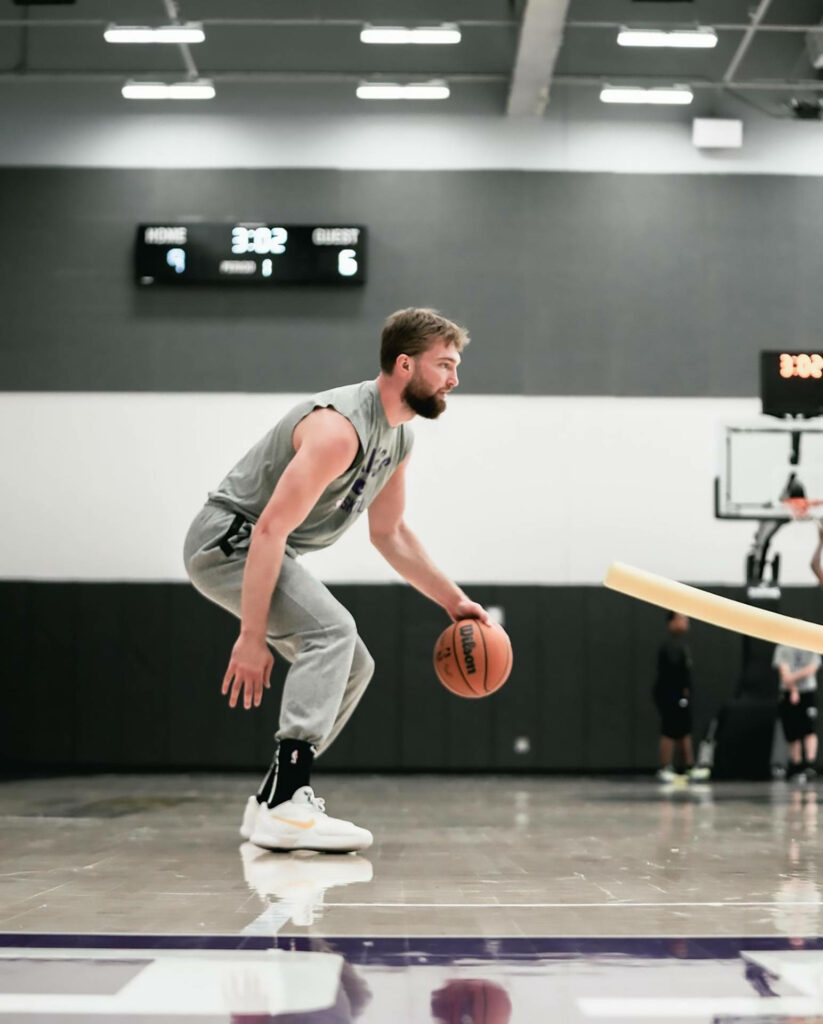 Domantas Sabonis practicing intense dribbling drill on polished indoor court in modern gym Wallpaper