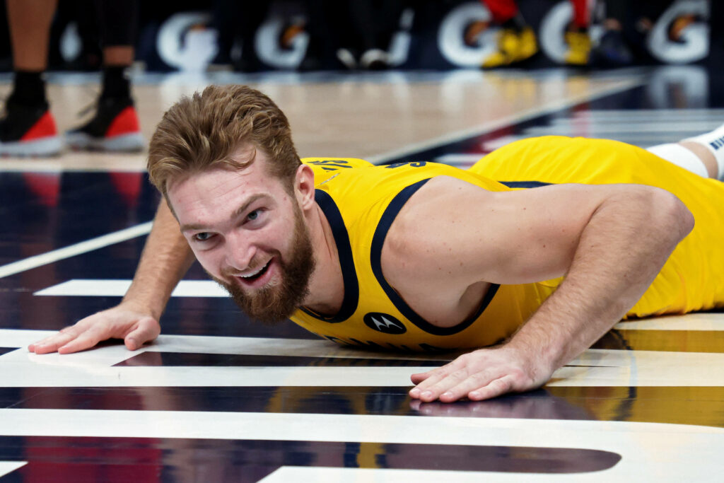 Domantas Sabonis in yellow jersey smiling determined during intense basketball game action shot Wallpaper