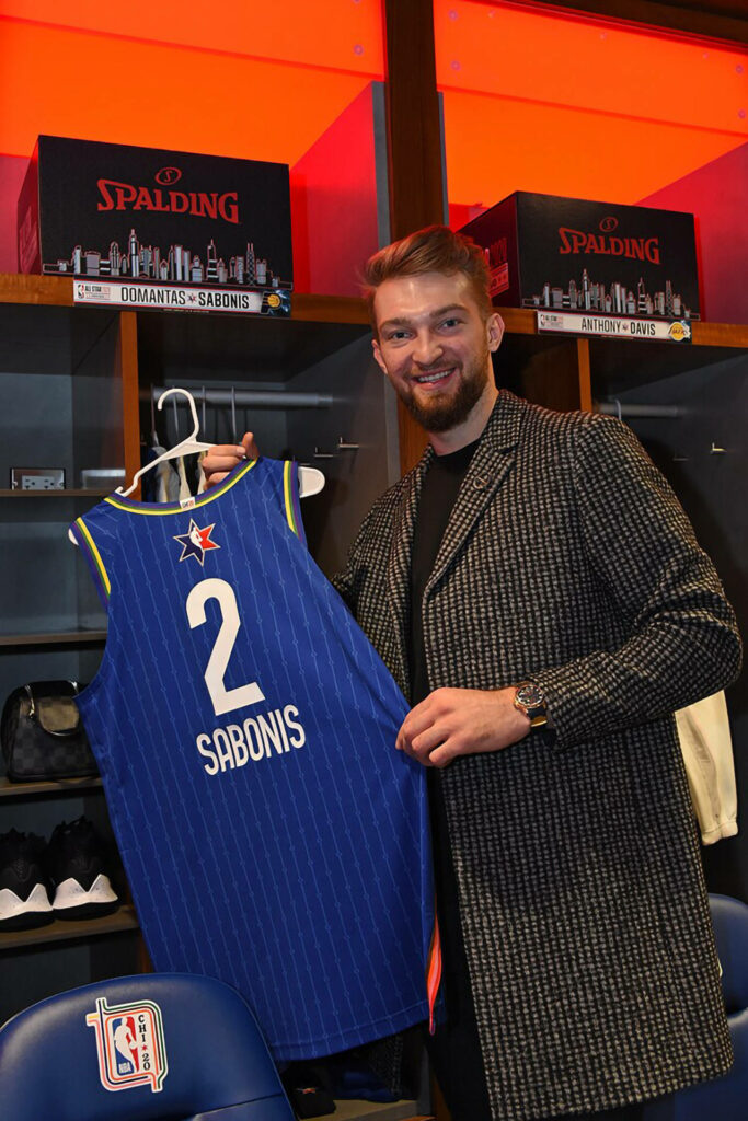 Domantas Sabonis holds blue All-Star 2020 jersey number 2 in lit locker room celebrating NBA achievement Wallpaper