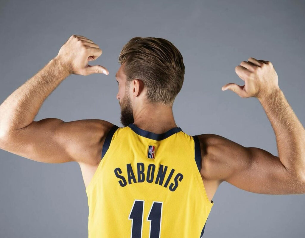 Domantas Sabonis muscular build in yellow NBA jersey number 11 with blond hair on gray background Wallpaper