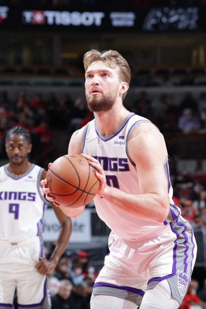 Domantas Sabonis focused free throw Sacramento Kings white purple uniform stadium lights background Wallpaper
