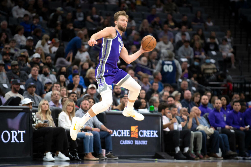 Domantas Sabonis mid-air in Sacramento Kings purple jersey action packed basketball wallpaper background