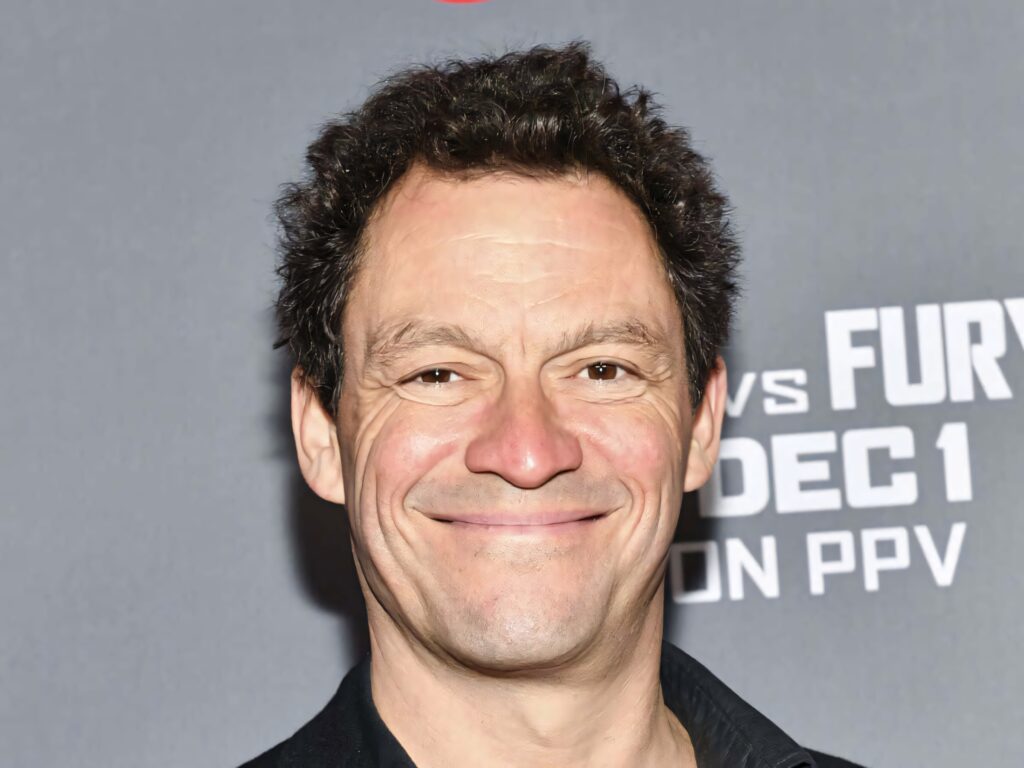 Dominic West smiling confidently in high-resolution wallpaper with sleek gray background lighting