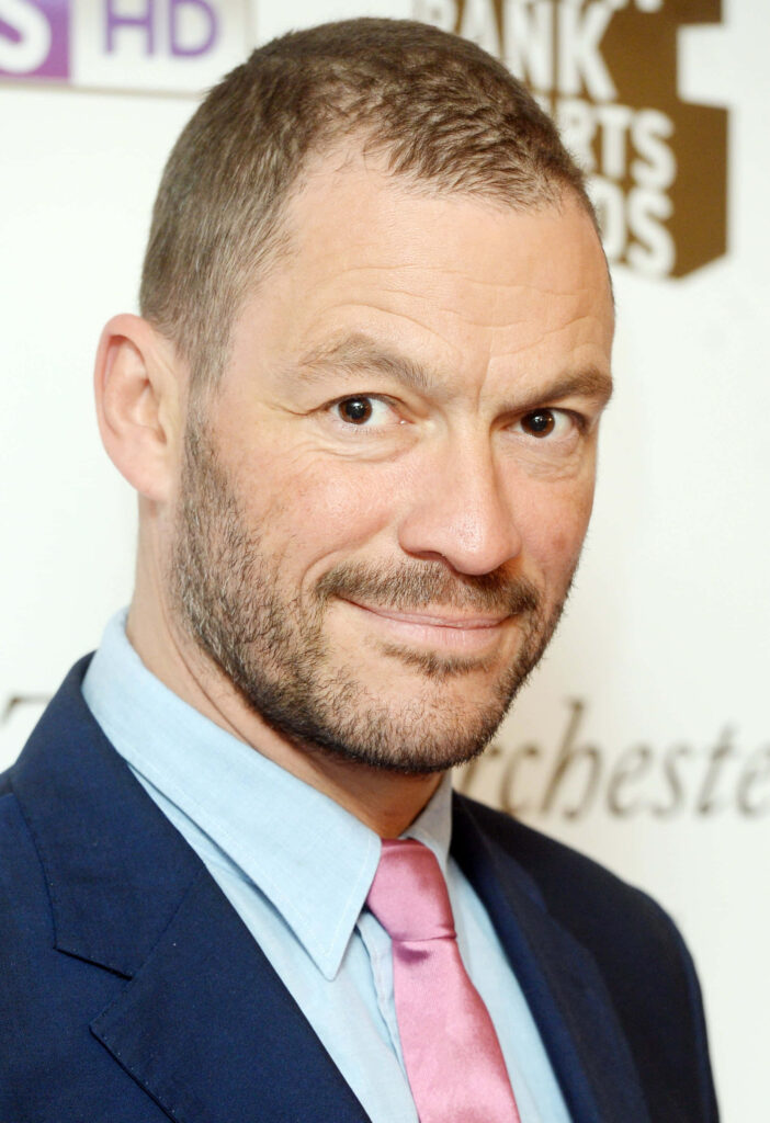 Dominic West in blue suit pink tie confident expression professional event blurred background wallpaper