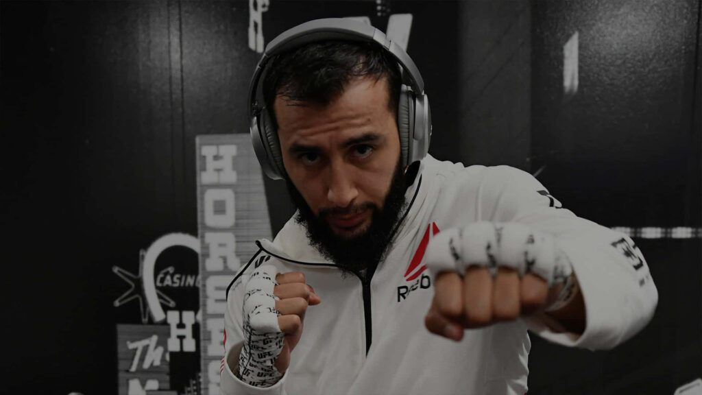 Dominick Reyes focused pre-fight in white Reebok hoodie taped hands fighting stance wallpaper background