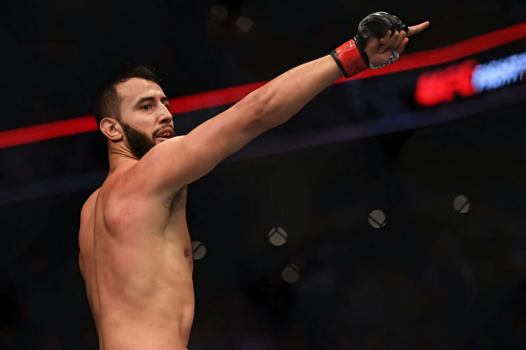 Dominick Reyes shirtless in octagon victory pose MMA fight intense athletic physique arena background Wallpaper