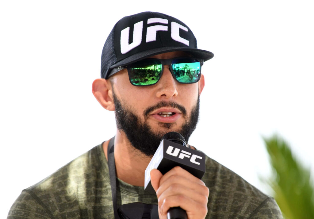 Dominick Reyes UFC fighter speaking at press conference wearing UFC cap and reflective sunglasses Wallpaper