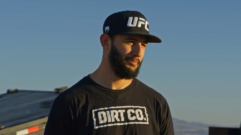 UFC fighter Dominick Reyes outdoors in sunlight wearing black cap and Dirt Co t-shirt wallpaper