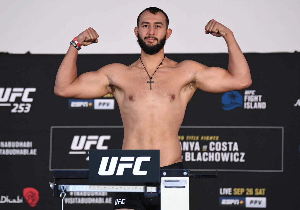Dominick Reyes UFC weigh-in flexing arms on scale with bold branding and focused fight night pose Wallpaper