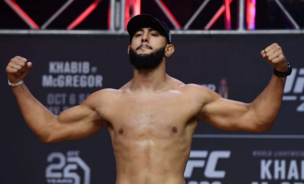 Dominick Reyes shirtless UFC weigh-in flexing muscles confident stance black cap dramatic lighting Wallpaper