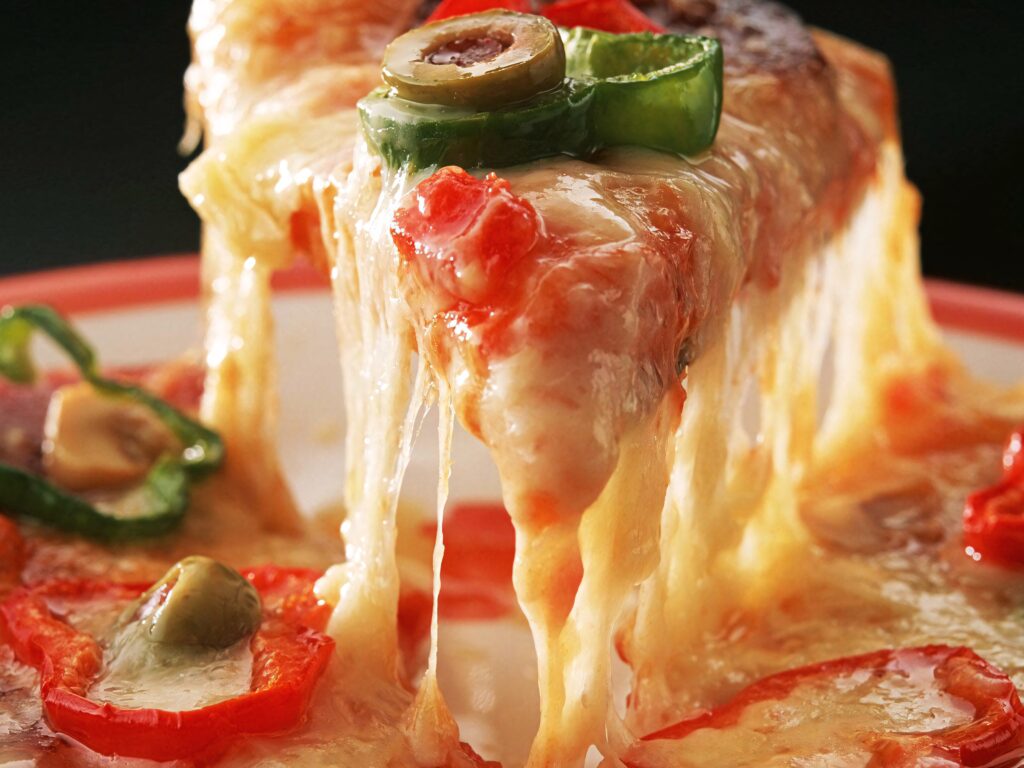 Close up of Domino's Pizza slice with melted cheese red bell peppers green jalapeños and olives Wallpaper