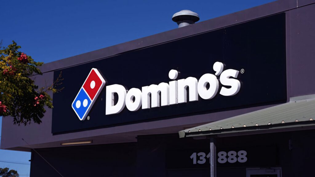 Dominos Pizza outlet at night with illuminated bold signage and vibrant modern storefront lighting Wallpaper