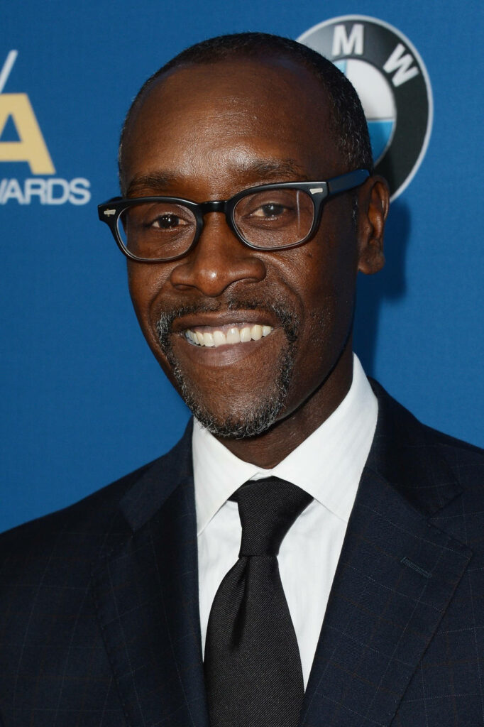 Don Cheadle in dark checked suit white shirt black tie at formal event blue logo backdrop vibrant colors Wallpaper