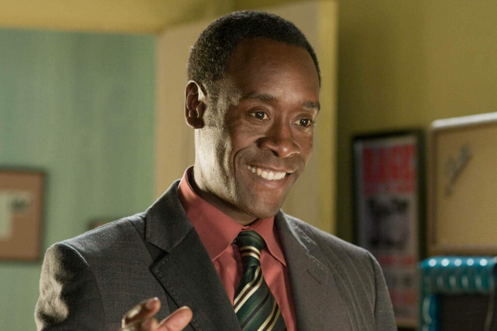 Don Cheadle mid-performance in sharp suit patterned tie warm background vibrant wallpaper