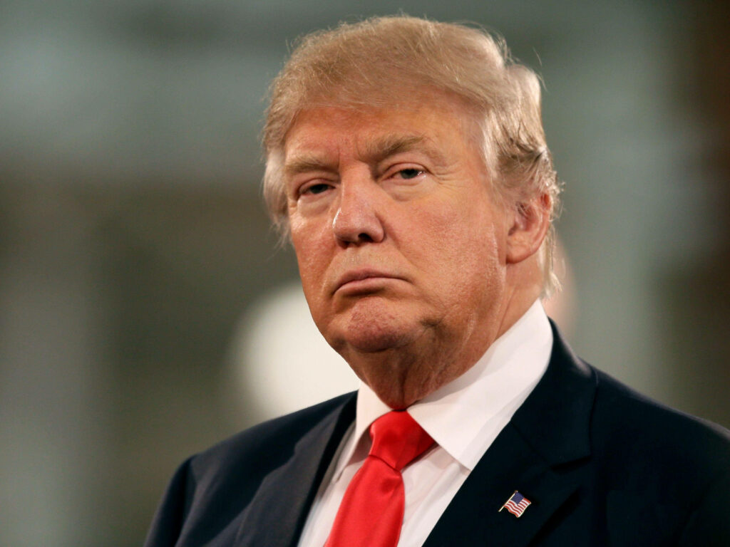 Donald Trump stern frown dark suit red tie natural light blurred background wallpaper