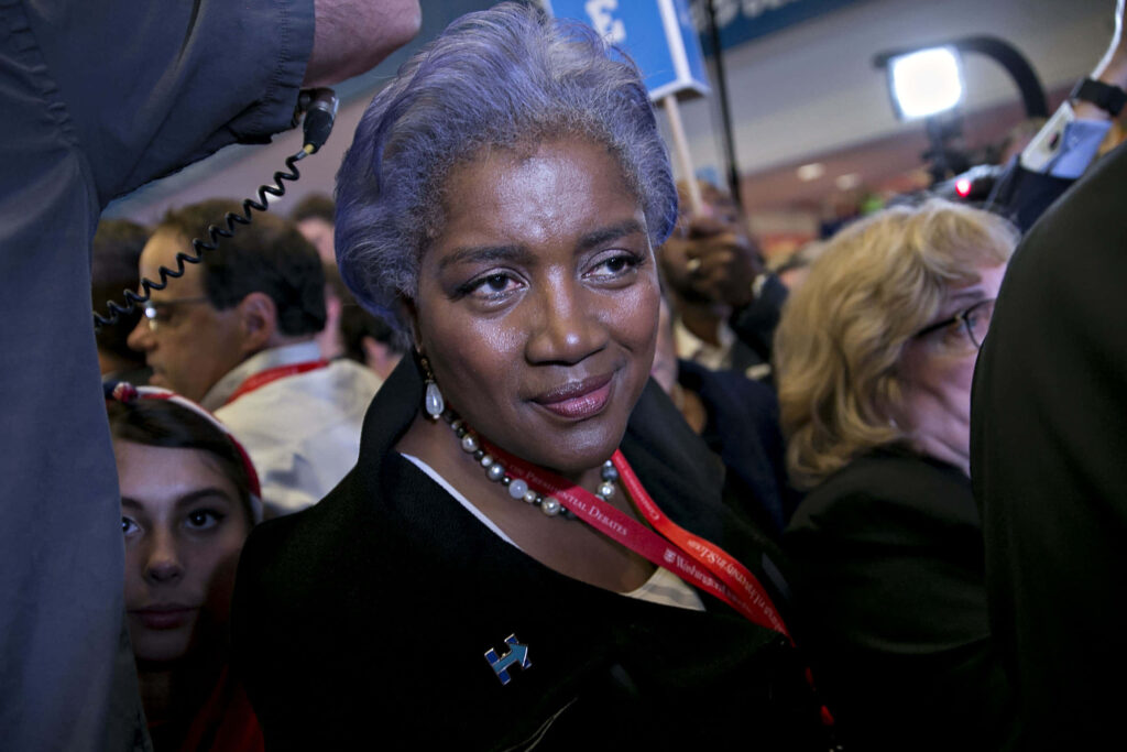 Donna Brazile confidently amid reporters and camera flashes at a dynamic political event wallpaper