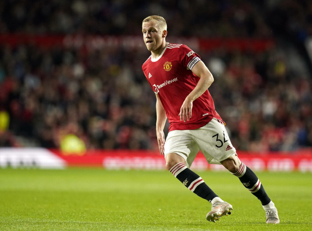 Donny van de Beek running on green pitch in Manchester United kit during bright stadium match Wallpaper