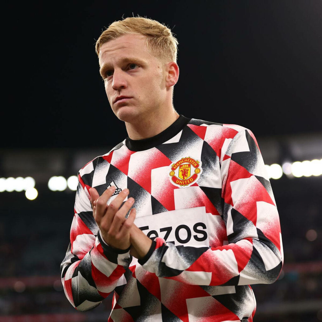 Donny van de Beek clapping in vibrant Manchester United training top with stadium lights background Wallpaper