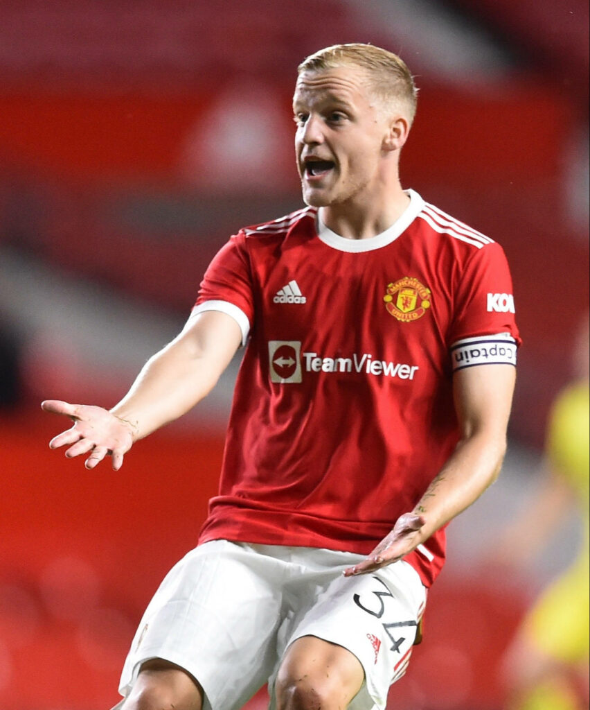 Donny van de Beek in Manchester United kit mid-action with bent knees in vibrant stadium Wallpaper